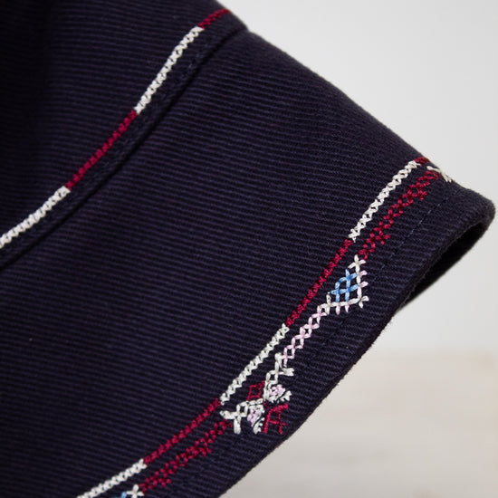 Navy blue fabric with embroidered patterns on a light gray background