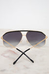 Gold-framed sunglasses with dark gradient lenses on a marble surface