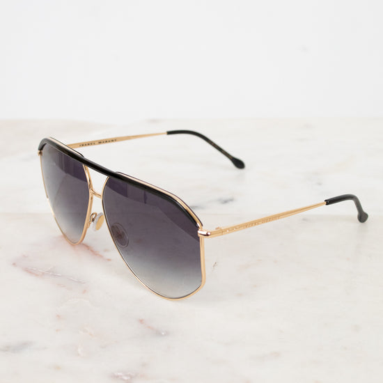 Aviator sunglasses with gold frame and dark lenses on a marble surface