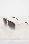 Aviator sunglasses with gold frame and dark lenses on a marble surface