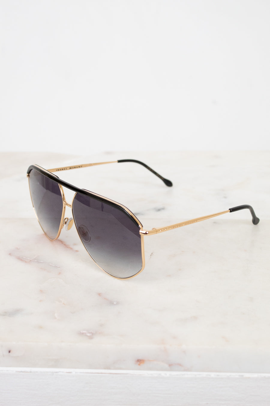 Aviator sunglasses with gold frame and dark lenses on a marble surface