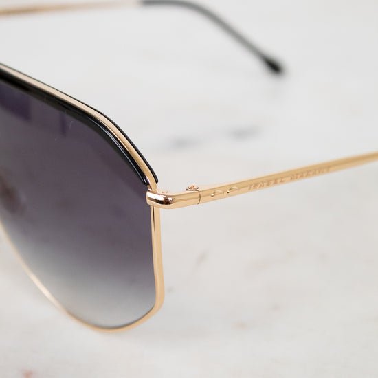 Gold-framed sunglasses with gradient lenses on a light gray background