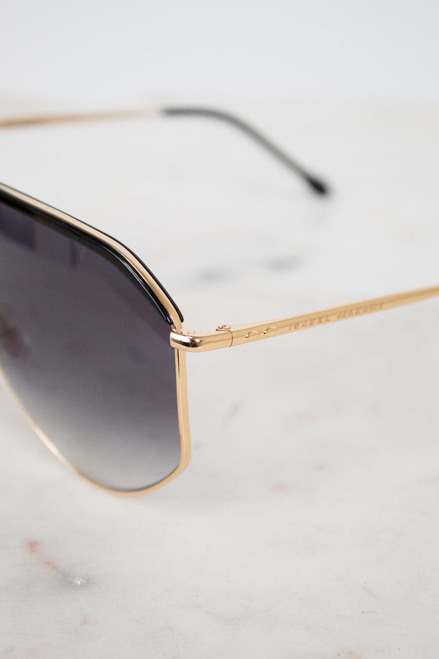 Gold-framed sunglasses with gradient lenses on a light gray background