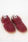 A pair of vintage maroon suede sneakers with triple Velcro straps, white lining, and gum soles, displayed on a light marble surface against a white background.