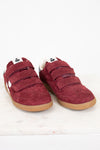 A pair of maroon suede shoes with triple Velcro straps and gum soles, displayed on a light marble surface against a white background.
