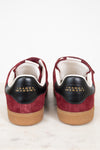 A pair of Isabel Marant sneakers shown from the back, featuring burgundy suede and black leather details with gold lettering, white lining, and tan rubber soles, set against a clean white background.