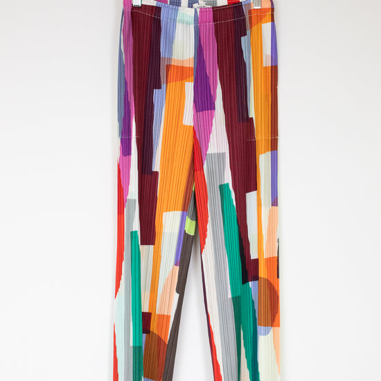 Colorful patterned pants on a hanger against a white background