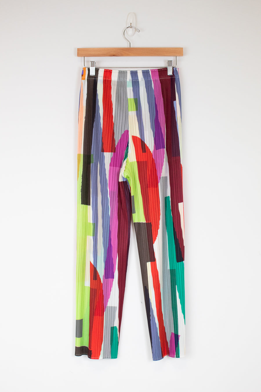 Colorful patterned pants on a hanger against a white background