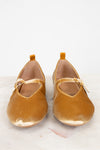 Pair of mustard yellow shoes with a strap on a light background