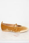 Gold velvet flat shoe with a gold buckle on a light gray background
