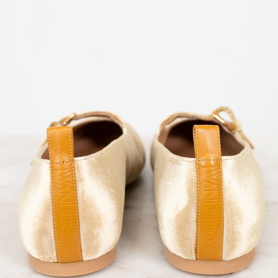 Pair of gold shoes with orange accents on a white background