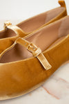 Pair of mustard yellow velvet shoes with a strap on a light background