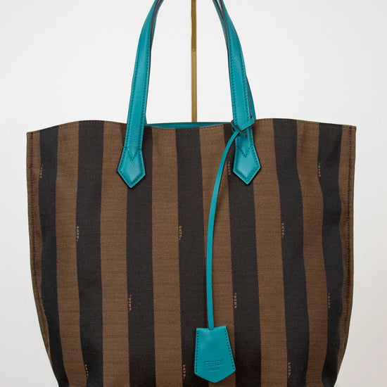 Striped tote bag with turquoise handles and trim on a white background
