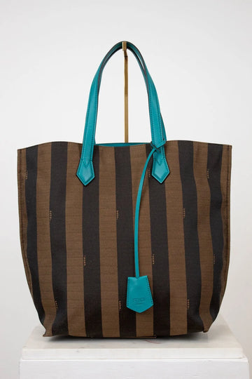 Striped tote bag with turquoise handles and trim on a white background