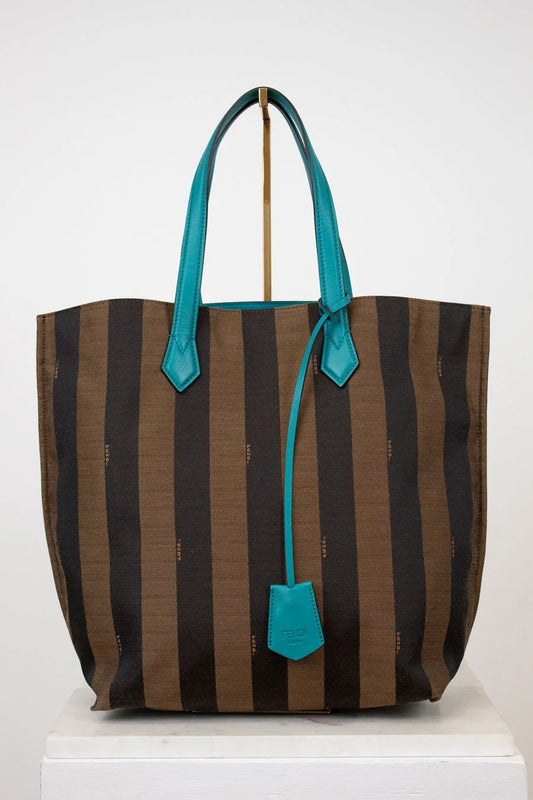 Striped tote bag with turquoise handles and trim on a white background