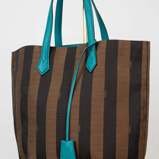 Striped tote bag with turquoise handles and accents on a white background