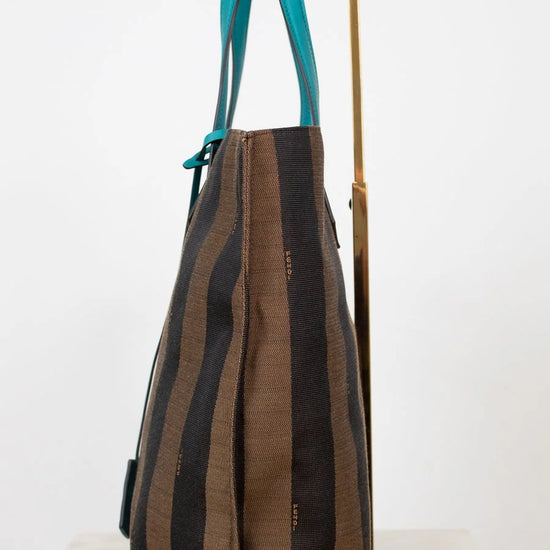 Striped handbag with turquoise handle on a white background