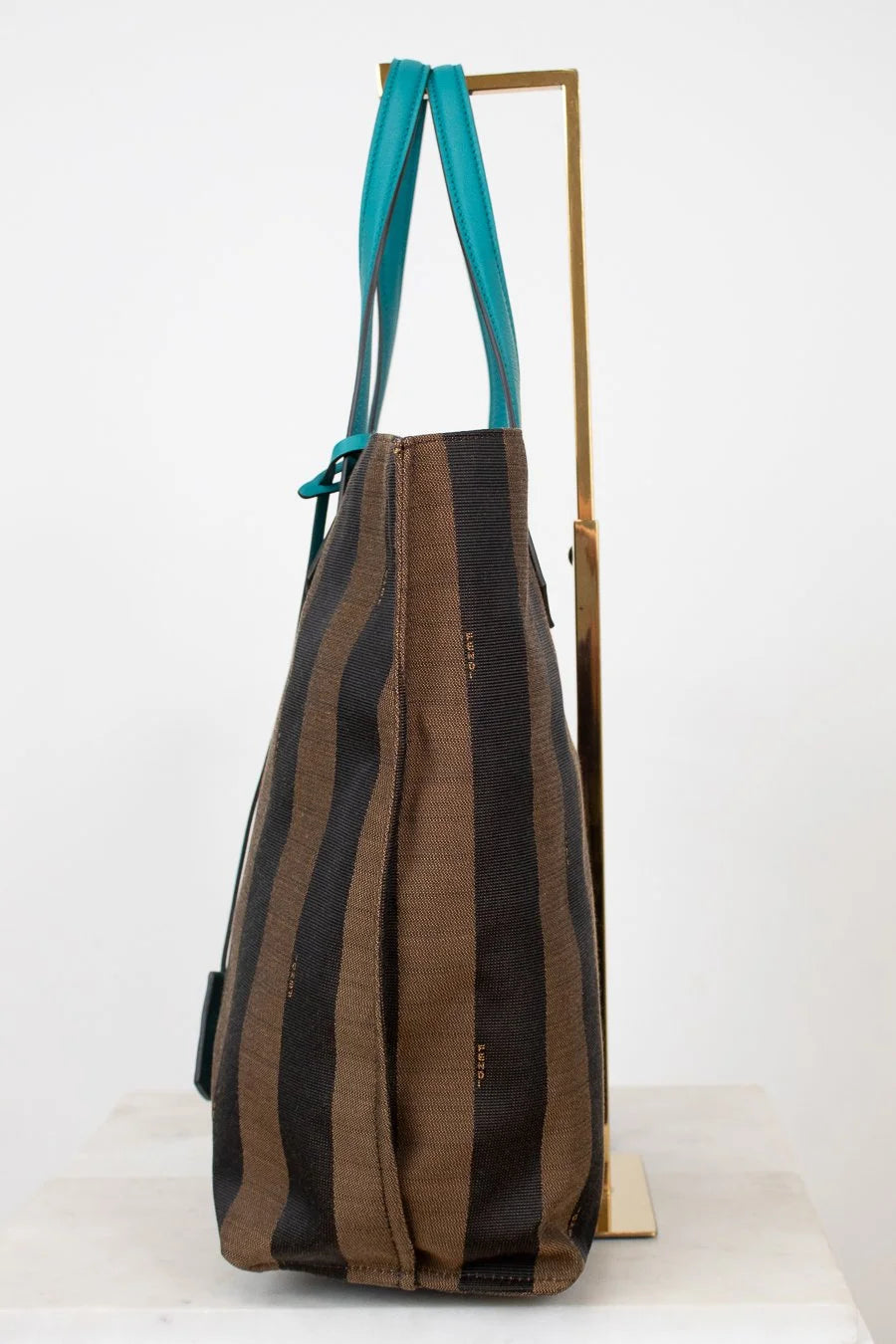 Striped handbag with turquoise handle on a white background