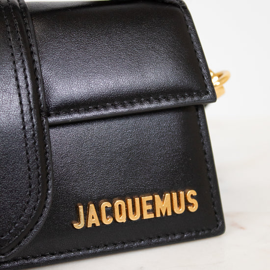 Black handbag with 'Jacquemus' branding on a marble surface