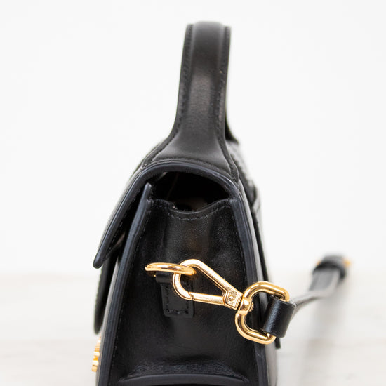 Black handbag with gold clasp on a light background
