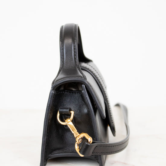 Black handbag with gold clasp on a white background