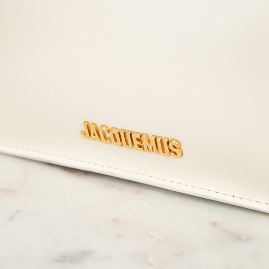 White clutch bag with gold 'Jacquemus' logo on a marble surface
