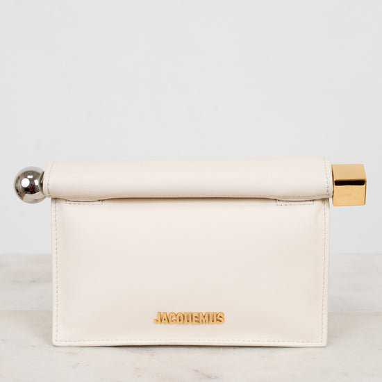 Cream-colored clutch with gold and silver accents on a marble surface