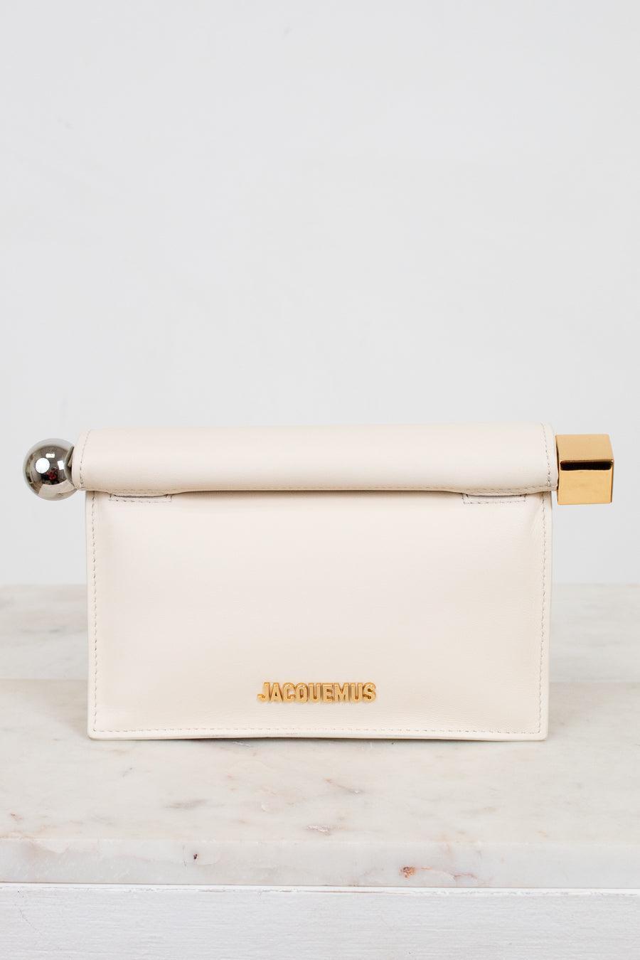 Cream-colored clutch with gold and silver accents on a marble surface