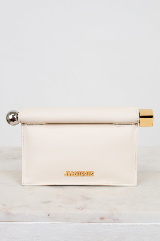Cream-colored clutch with gold and silver accents on a marble surface