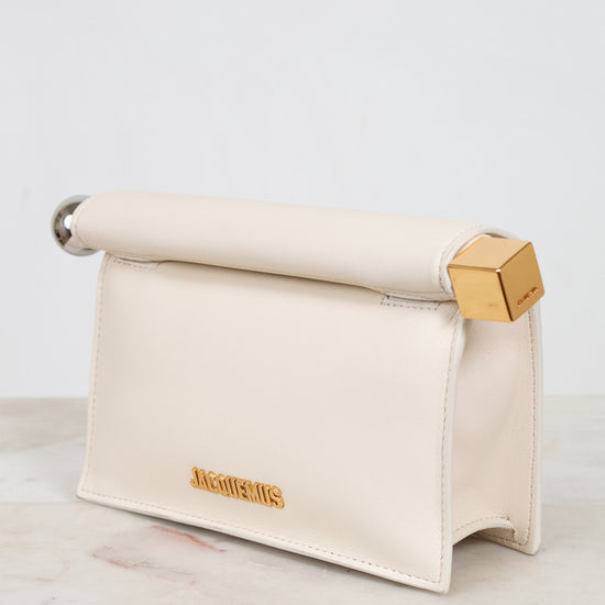 Cream-colored pouch with gold and silver accents on a marble surface