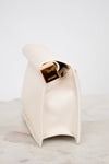 White side profile of clutch with gold  accent on a marble surface