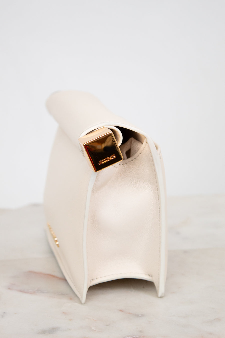 White side profile of clutch with gold  accent on a marble surface