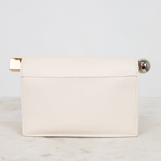 White clutch bag with gold and silver accents on a light gray background
