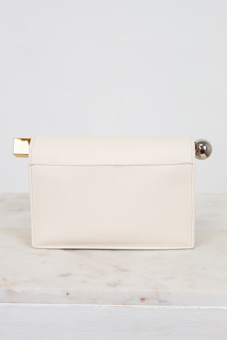 White clutch bag with gold and silver accents on a light gray background