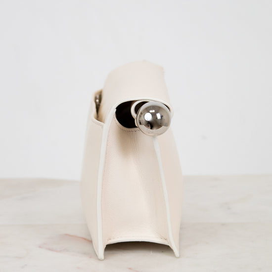 White side profile of clutch with a silver accent on a light marble surface.