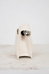 White side profile of clutch with a silver accent on a light marble surface.
