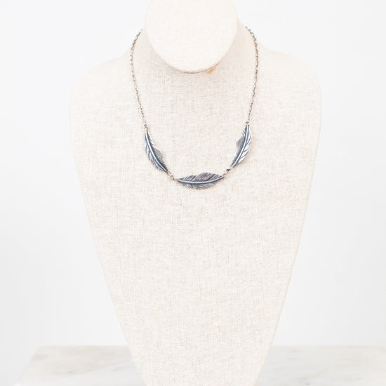 Feather necklace on a mannequin bust against a white background