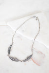 Silver feather necklace on a marble surface