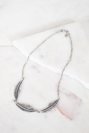 Silver feather necklace on a marble surface