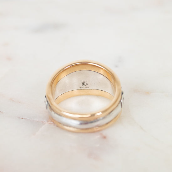 Silver and gold ring with brand logo on white background