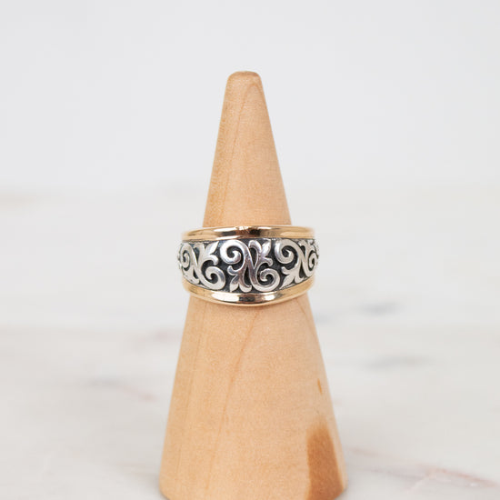 Silver ring on a wooden cone against a white background