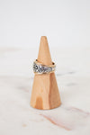 Wooden ring holder with a silver ring on a marble surface