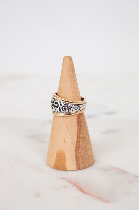 Wooden ring holder with a silver ring on a marble surface
