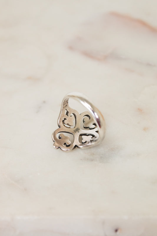 Silver ring with intricate design on a marble surface