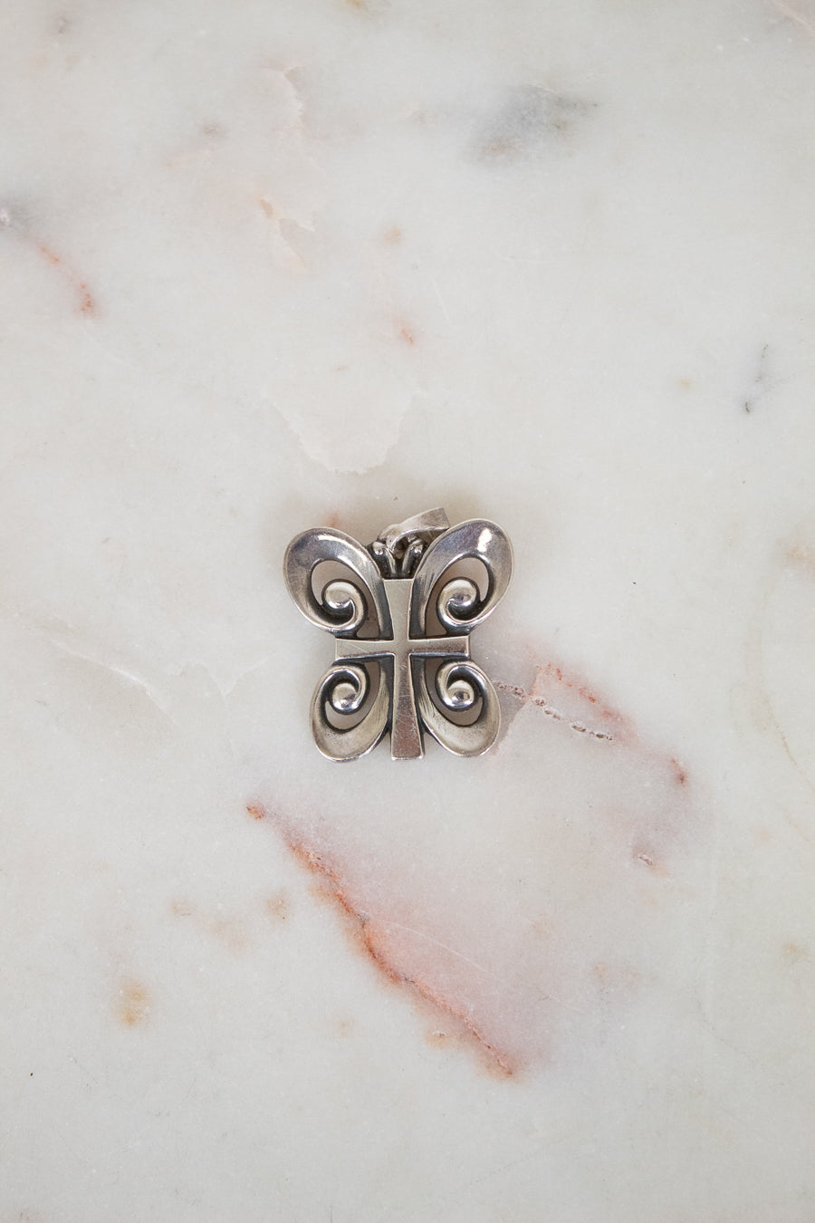 Silver butterfly-shaped object on a marble surface