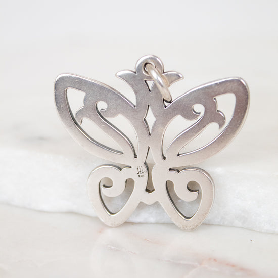 Silver butterfly pendant on a marble surface