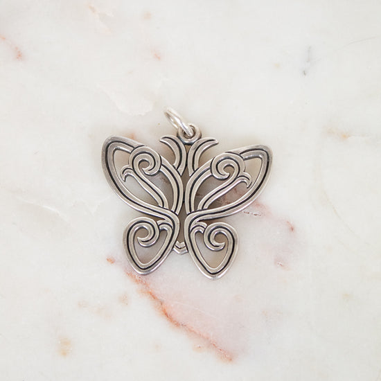 Silver butterfly pendant on a marble background