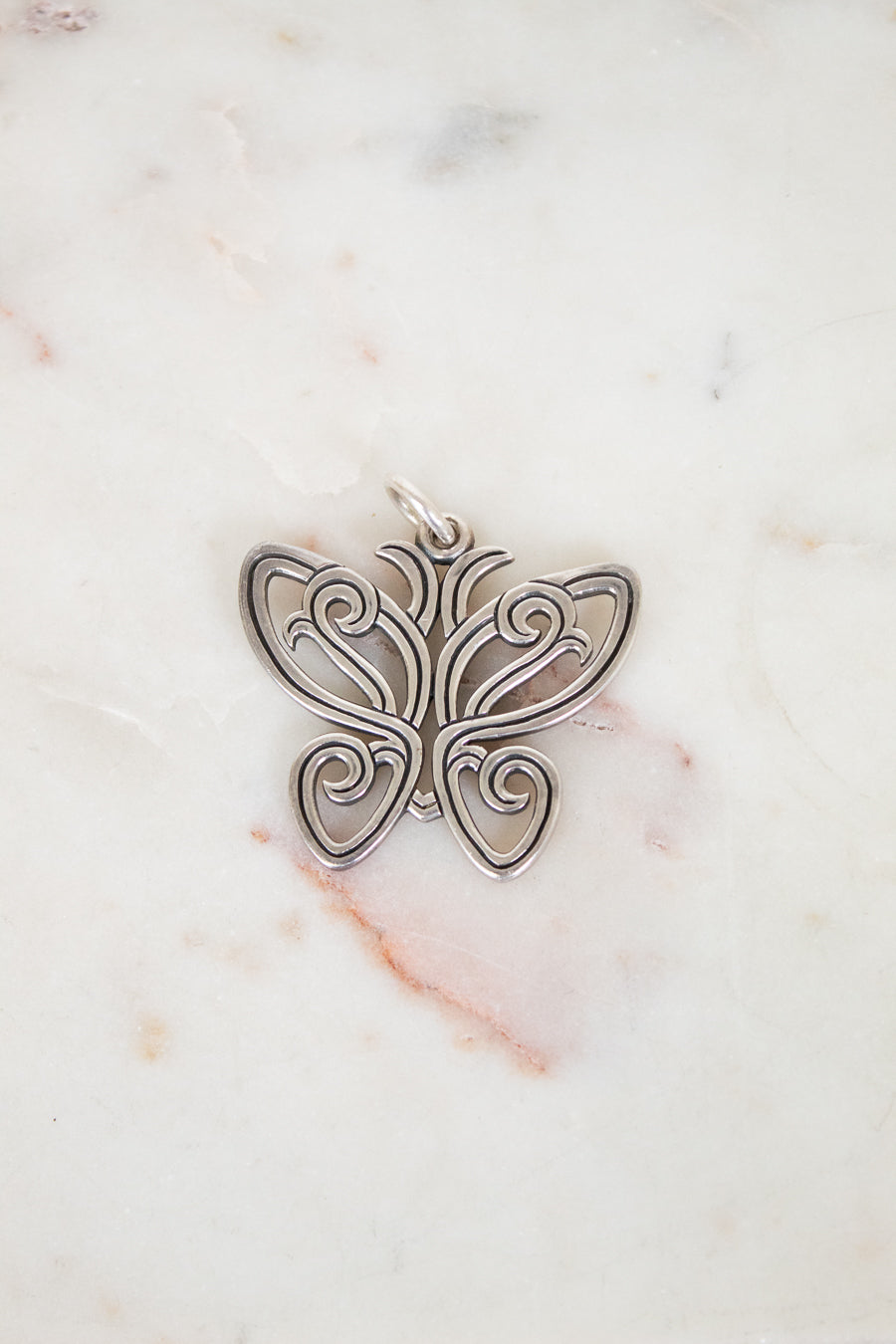 Silver butterfly pendant on a marble background