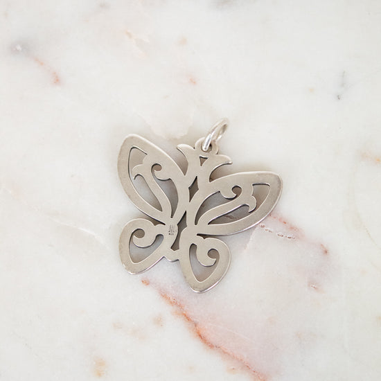 Silver butterfly pendant on a marble surface