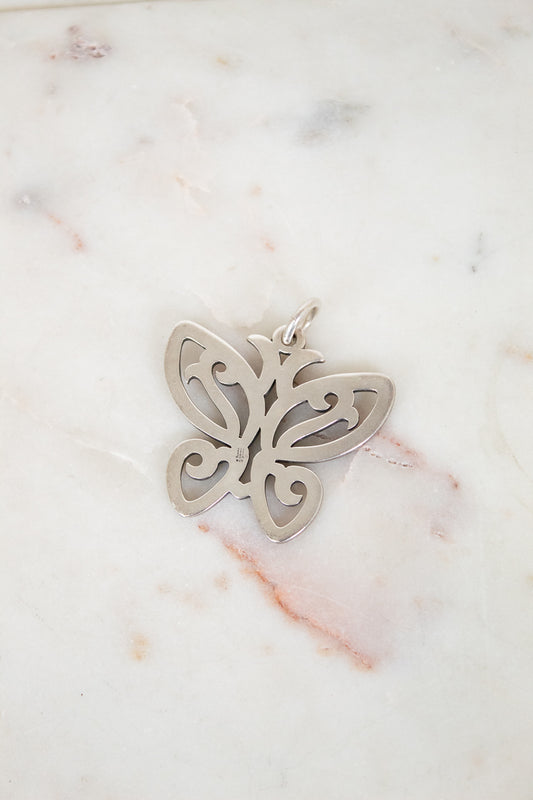Silver butterfly pendant on a marble surface